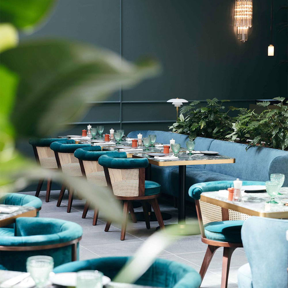 George dining chairs in blue tones, natural rattan, and smoked walnut wood at Montecito Paris Restaurant.