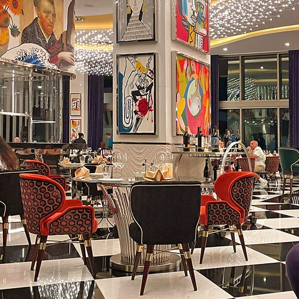 NOI Restaurant at Hotel Mousai featuring several Louis I and Louis dining chairs in dark blue and red tones.