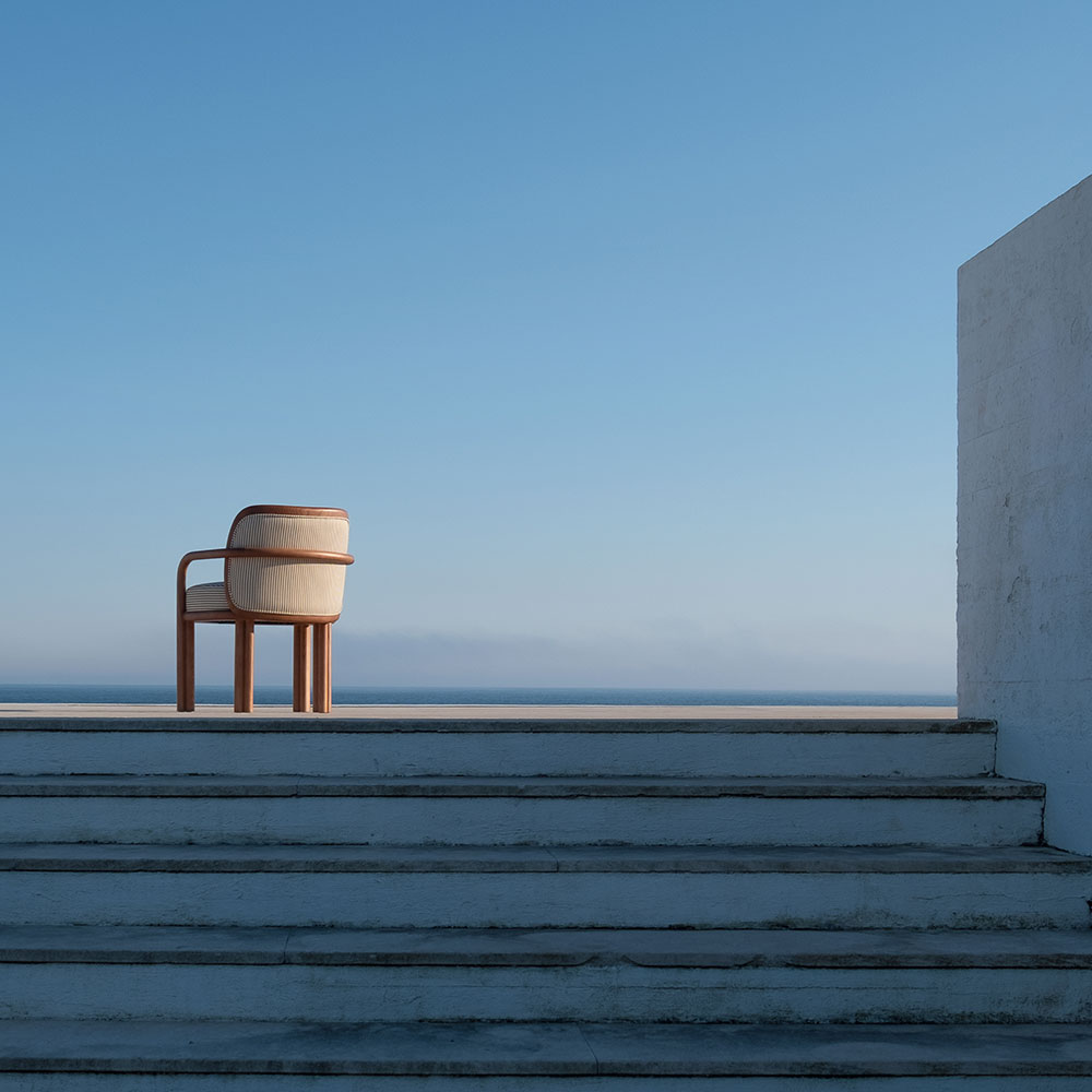 James dining chair in oak and striped fabric at the top of stairs, with a vibrant blue sky in the background.