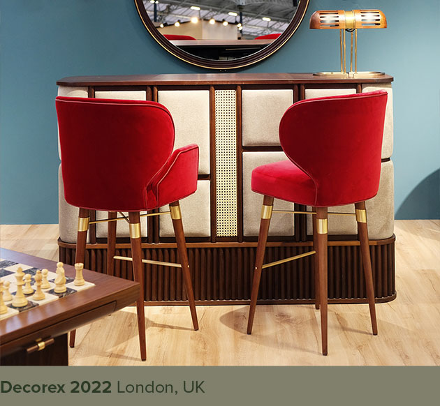 Louis I and Louis bar chairs upholstered in red, placed beside the Tom bar counter and Turing table lamp at Decorex London.