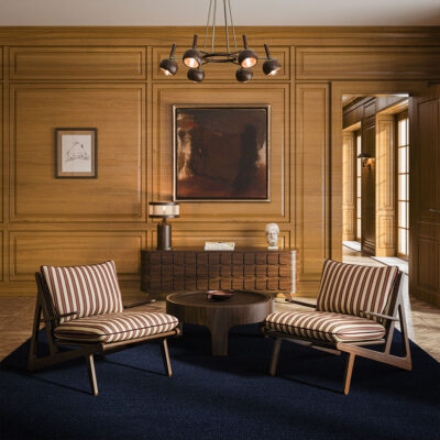 Living room featuring the Moore Armchair upholstered in striped fabric, alongside the Churchill Center Table, Elliott Sideboard, Hampshire Table Lamp, and Essen Suspension Lamp by Wood Tailors Club.